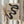 May include: Hands holding a framed beige poster with flowing black curved shapes resembling ribbons or smoke. The poster displays "BAUHAUS" text with "FORM FOLLOWS FUNCTION" subtitle and dates "Weimar Juni - September 1919 Stuttgart Kunstgeboude am Schlossplatz." Person wears cream-colored clothing with gathered sleeves, holding dried pampas grass stems. Light wooden frame against soft neutral background with natural window lighting.