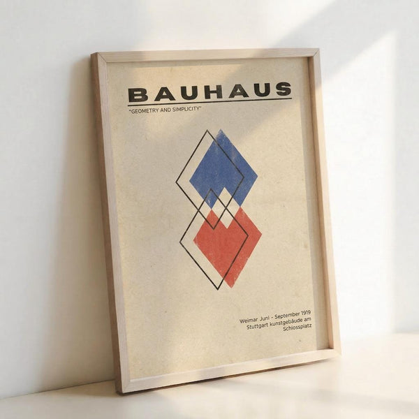 May include: Framed Bauhaus poster with geometric diamond shapes in blue and red overlapping with black outlines on cream background. Light wood frame leaning against white wall in bright natural lighting. Vintage-style art print featuring "Geometry and Simplicity" subtitle and German exhibition text at bottom.