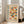 May include: A framed Bauhaus-style poster with geometric semicircles in red, orange, blue and yellow arranged in a grid pattern. The cream-colored print features "BAUHAUS" and "MODERN ART" text along the left side, with German exhibition details at top and bottom. The white wooden frame leans against a white wall beside a beige upholstered chair in a bright room with large windows.