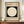 May include: Framed Bauhaus-style poster with cream background featuring large white circle on black square, dated 1919, with German text below. Displayed on wooden sideboard next to white ceramic vase and stacked books against cream wainscoted wall.
