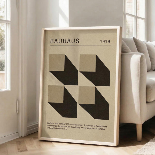 May include: Framed Bauhaus-style poster with geometric black arrow shapes on beige background, displayed in bright living room with beige sofa, white walls, and large windows. The vintage-inspired art print features clean typography reading "BAUHAUS 1919" and German text below the minimalist design.
