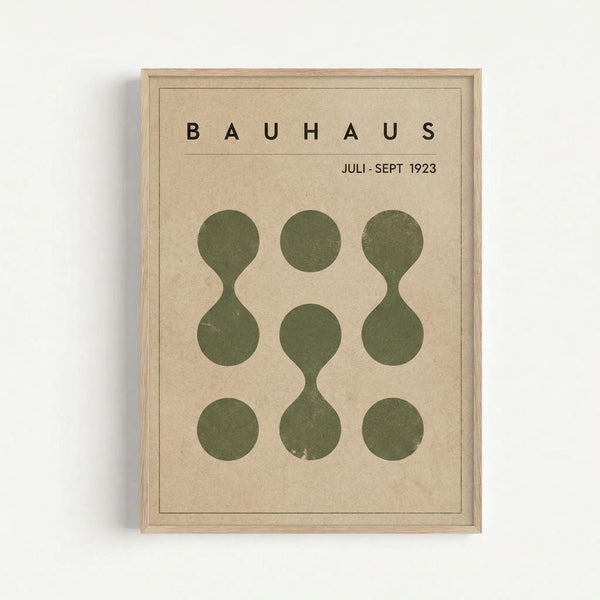 A vintage-style poster with cream background featuring the word "BAUHAUS" in bold black letters at the top, followed by "JULI-SEPT 1923" underneath. The main design shows nine olive green circular shapes arranged in a 3x3 grid - four are simple circles while five are connected hourglass or figure-8 shapes. The poster is displayed in a light wood frame against a white wall, showing the minimalist geometric design characteristic of Bauhaus art movement aesthetics.