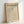 May include: Framed Bauhaus poster with minimalist cone line drawing on beige background, displayed in light wood frame leaning against white wall. Features "LESS IS MORE" motto and German exhibition text from 1919 Stuttgart.