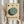 May include: Person holding framed Bauhaus-style poster with geometric design featuring overlapping circles in sage green and dark green on cream background, three small circles above, black text below. Light wood frame, neutral room setting with dried pampas grass and soft natural lighting.