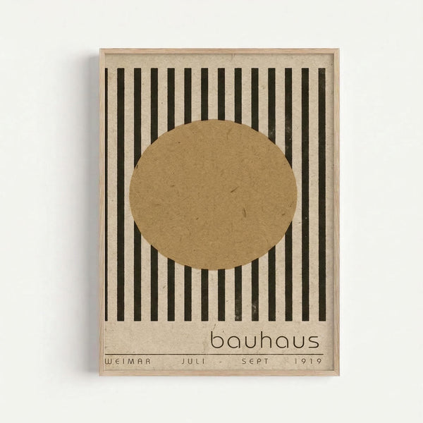 Minimalist poster with vertical black stripes on beige background, featuring a large tan circle in the center. Text reads "bauhaus" below the circle and "WEIMAR JULI - SEPT 1919" at the bottom. The design is displayed in a simple light wood frame against a white wall, showcasing the geometric Bauhaus aesthetic with earthy, muted tones.