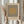 May include: Person in beige clothing holding a framed Bauhaus-style poster featuring vertical black lines with a tan circle overlay on cream background. Dried pampas grass visible to the left. Natural lighting creates soft shadows on neutral wall backdrop.
