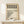 May include: Framed Bauhaus poster with geometric black and white circles pattern and "Form Follows Function" text, displayed on light wood surface next to small wrapped gift with twine and greenery sprig, against cream wall with natural lighting