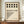 May include: Framed Bauhaus-style poster with geometric black circles and dots pattern on cream background, displayed on wooden console table beside white ceramic vase and stacked books in modern interior with white paneled walls