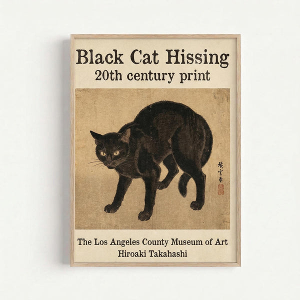 A framed vintage-style print featuring a black cat in a defensive, hissing pose with arched back and alert stance. The cat has striking yellow-orange eyes and detailed black fur rendered in an Asian woodblock print style on aged beige paper. Japanese characters and a red seal mark appear on the right side. Text above reads "Black Cat Hissing 20th century print" and below credits "The Los Angeles County Museum of Art, Hiroaki Takahashi." The print is displayed in a simple light wood frame