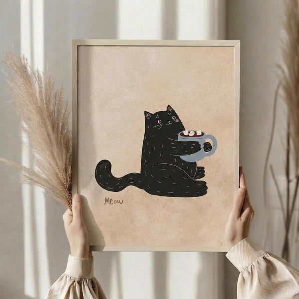 May include: Person in beige sweater holding framed art print featuring black cat with coffee mug, standing near dried pampas grass against neutral curtained background. The illustration shows a charming black cat holding a blue mug with marshmallows, drawn in simple line art style on cream paper with "Meow" text below. Natural wood frame complements the warm, cozy aesthetic.
