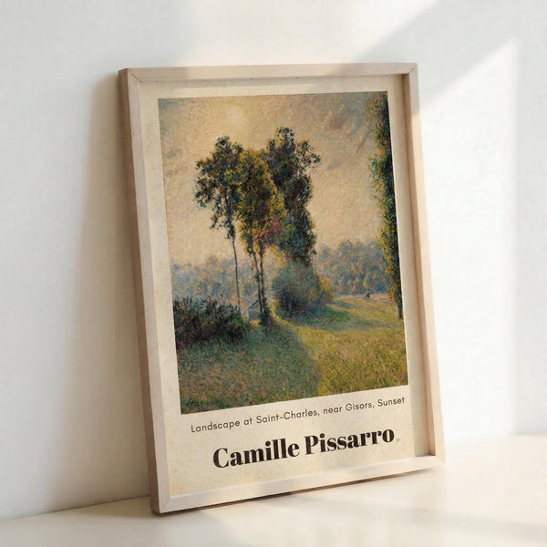 May include: Framed art print of an impressionist landscape painting featuring tall trees along a country path at sunset, with soft golden and green tones throughout the pastoral scene. The wooden frame leans against a white wall, showing the cream-colored matting and black text identifying the artwork and artist below the image.