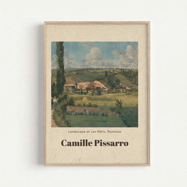 May include: Framed art print showing Camille Pissarro's impressionist landscape painting of rural French countryside with rolling green fields, farm buildings with red-tiled roofs, tall poplar trees, and cloudy blue sky. The print features cream matting in a light wood frame, mounted on a white wall. The painting depicts pastoral farmland with small figures working in the fields and a winding path through the valley.