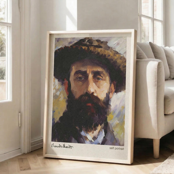 May include: Framed print of a bearded man wearing a wide-brimmed hat, painted in impressionist style with visible brushstrokes in earth tones and muted colors. The artwork is displayed in a light wood frame, leaning against a white wall next to a beige upholstered chair in a bright, minimalist room with large windows and natural lighting.