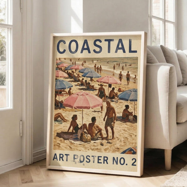 May include: Framed vintage-style beach scene poster leaning against white wall next to beige sofa in bright living room. Artwork shows crowded sandy beach with pink and blue striped umbrellas, sunbathers, and people walking along shoreline. Text reads "COASTAL" at top and "ART POSTER NO. 2" at bottom in navy blue letters on cream background. Natural wood frame, hardwood floors visible.