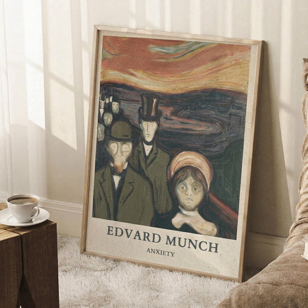 May include: Framed art print leaning against white wall on textured white rug, showing expressionist painting of anxious figures in dark coats with dramatic swirling sky in orange and red tones. Wooden side table with coffee cup visible nearby, natural window light creating soft shadows across the scene.