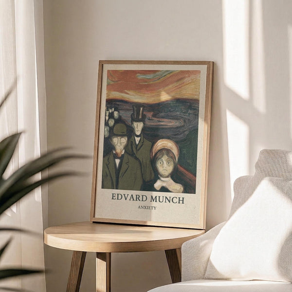 May include: Framed art print displaying Edvard Munch's expressionist painting with figures in dark coats and a woman in white bonnet against swirling sky in oranges and blues, positioned on round wooden side table next to beige upholstered chair with plant shadows cast on cream wall