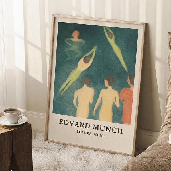 May include: Framed art print leaning against white wall on fluffy white rug, showing stylized figures in teal water - some swimming, others standing on shore in cream and coral tones. Light wood frame, cozy room setting with coffee cup on wooden surface and soft lighting from window.