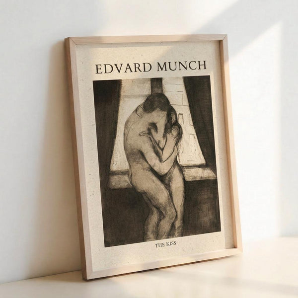 May include: Framed reproduction of Edvard Munch's "The Kiss" artwork in light wood frame, showing two nude figures embracing by a window with dark curtains, rendered in sepia and black tones with sketchy, expressive linework, displayed on white surface against white wall with soft natural lighting