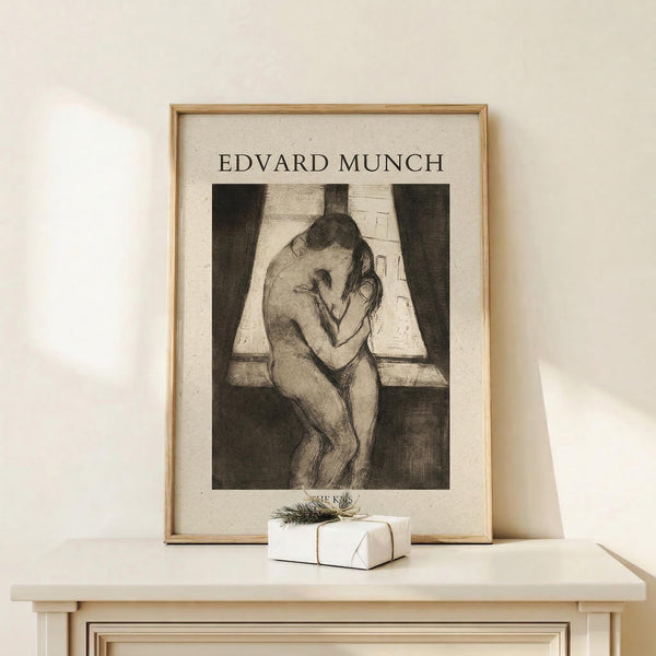 May include: Framed poster print of Edvard Munch's "The Kiss" artwork showing two embracing figures in black and white sketch style, displayed in light wood frame on white wooden console table with small wrapped gift box beside it against cream wall