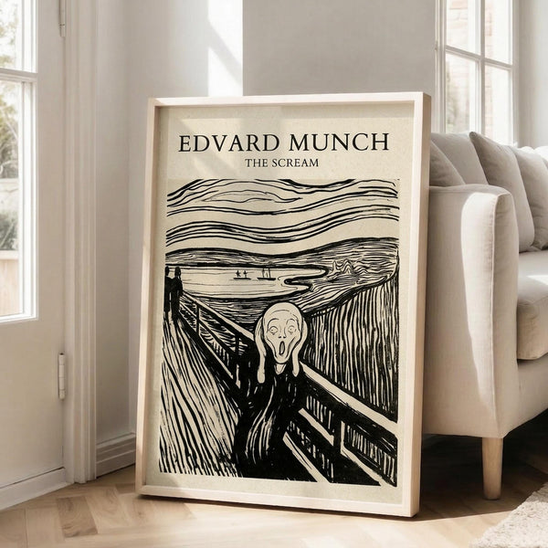 May include: Framed art print of Edvard Munch's iconic expressionist woodcut showing an agonized figure with hands to face on a bridge, with swirling sky lines above. Black ink on cream paper in light wood frame, leaning against white wall next to beige upholstered chair in bright, naturally-lit room with white window frames.