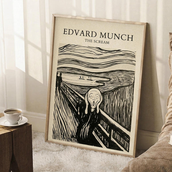 May include: Framed art print of Munch's The Scream displayed in a cozy living room corner. The black and white expressionist artwork shows a figure with hands to face on a bridge with swirling sky lines. Cream-colored mat in light wood frame, leaning against white wall near beige textured rug, wooden side table with white coffee cup, and neutral fabric furniture.