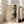 May include: Large framed art print leaning against white wall beside beige upholstered chair in bright living room with hardwood floors. The vintage-style artwork features dark silhouettes of pine trees overlaid with geometric lines and a partial circle on aged, cream-colored paper background in natural wood frame.