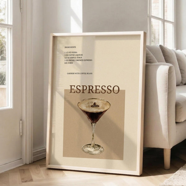 May include: Framed vintage-style espresso martini recipe poster in light wood frame, leaning against white wall next to beige sofa in bright living room with hardwood floors. Cream-colored print features dark cocktail in martini glass with coffee bean garnish, recipe ingredients listed above in brown text.