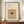 May include: Framed vintage-style cocktail recipe poster displaying espresso martini ingredients and garnish instructions above an illustration of a dark coffee cocktail in a martini glass with foam top and coffee bean garnish. Warm beige and brown tones with serif typography. Wooden frame sits on walnut sideboard next to white ceramic vase and stacked books against cream paneled wall.