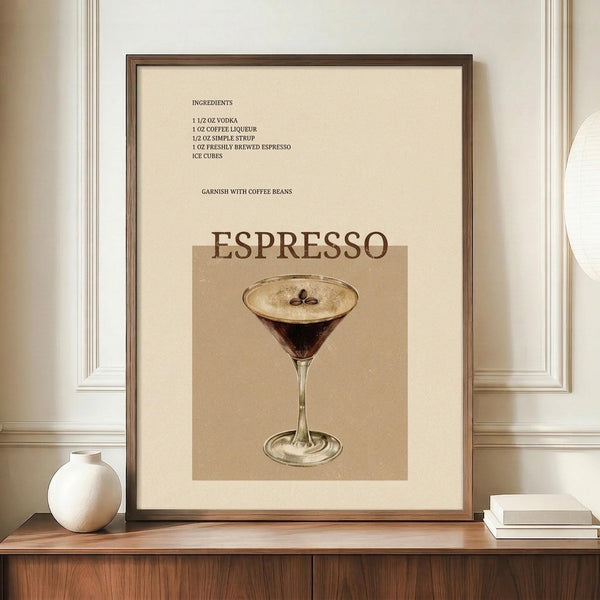 May include: Framed vintage-style cocktail recipe poster displaying espresso martini ingredients and garnish instructions above an illustration of a dark coffee cocktail in a martini glass with foam top and coffee bean garnish. Warm beige and brown tones with serif typography. Wooden frame sits on walnut sideboard next to white ceramic vase and stacked books against cream paneled wall.