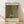 May include: Framed art print leaning against white wall on light wooden floor with natural sunlight casting shadows. The poster features Gustav Klimt's colorful garden painting with vibrant sunflowers, red poppies, and purple flowers in his distinctive decorative style. Cream-colored matting surrounds the artwork with museum text above and artist name below in serif font. Natural wood frame complements the warm, minimalist room setting.