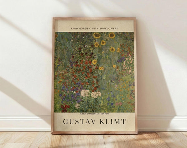 May include: Framed art print leaning against white wall on light wooden floor with natural sunlight casting shadows. The poster features Gustav Klimt's colorful garden painting with vibrant sunflowers, red poppies, and purple flowers in his distinctive decorative style. Cream-colored matting surrounds the artwork with museum text above and artist name below in serif font. Natural wood frame complements the warm, minimalist room setting.