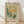 May include: Framed vintage-style botanical poster with sage green background featuring yellow daisy-like flowers and dark green foliage. Text reads "FLOWER MARKET" and "FLORANCE" in serif font. Light wood frame sits on wooden floor against white wall with soft natural lighting creating shadows.