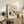 May include: Framed botanical poster with vintage-style floral design featuring purple and cream flowers with green foliage, displayed on rustic wooden sideboard alongside fern plant, ceramic vase, and stacked books in neutral-toned living room setting with beige armchair and throw pillows.