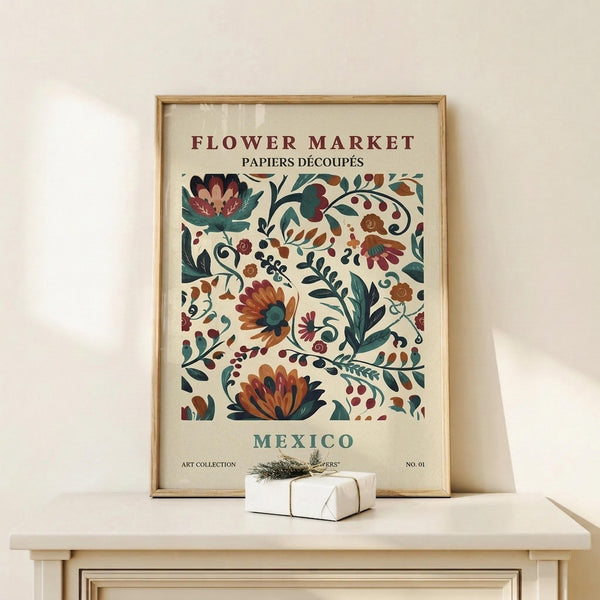 May include: Framed botanical poster with colorful floral pattern in burgundy, teal, and orange tones displayed on light wood shelf against cream wall. Small wrapped gift box with twine sits nearby. Vintage-inspired folk art style features decorative flowers, leaves, and berries in repeating design. Natural wood frame complements warm, minimalist home decor setting.