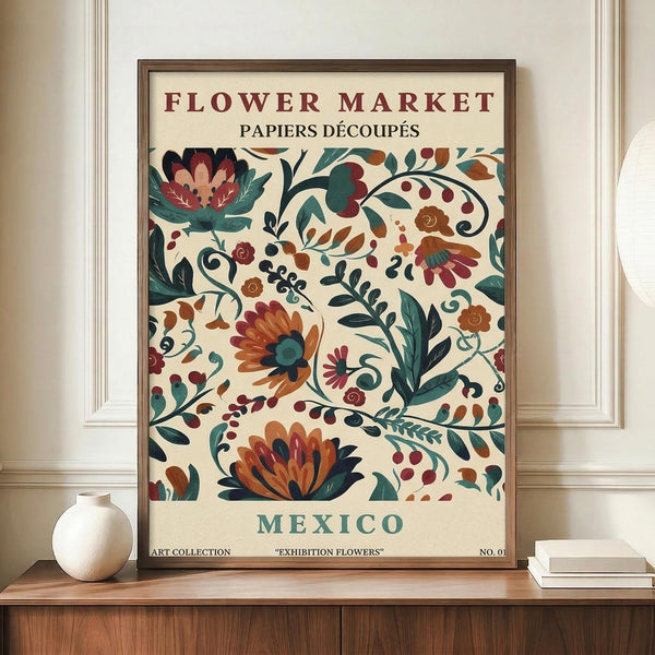 May include: Framed vintage-style botanical poster displayed on wooden credenza against white wainscoted wall. Features colorful folk art floral pattern with orange, burgundy, and teal flowers on cream background. French text at top, "Mexico" at bottom. White ceramic vase and books nearby for scale.