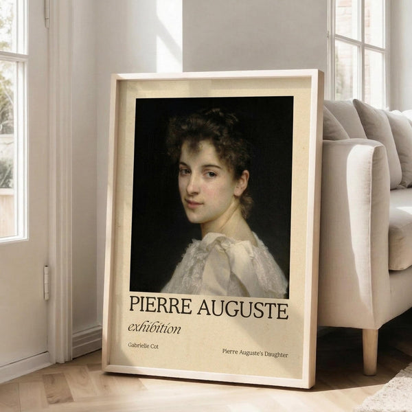 May include: Framed art print leaning against white wall beside beige sofa in bright living room. The poster features a classical portrait painting of a young woman with curly brown hair wearing a white dress against dark background. Exhibition-style layout with cream background and black text reading "PIERRE AUGUSTE exhibition" and "Gabrielle Cot" with "Pierre Auguste's Daughter" below. Light wood frame, hardwood floors.