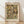 May include: Framed art print displaying Gustav Klimt's 1916 Portrait of Friederike Maria Beer, featuring a woman with long dark hair in an ornate patterned dress surrounded by colorful decorative figures and motifs in Klimt's distinctive Art Nouveau style. The poster has cream matting with black text identifying the artwork and artist, housed in a light wood frame, leaning against white walls on light wooden flooring with soft natural lighting.