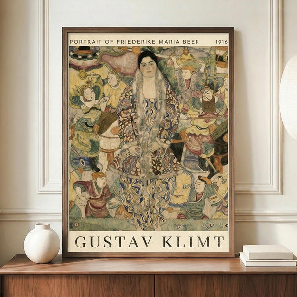 May include: Framed art print featuring Gustav Klimt's colorful portrait of a woman with long flowing hair surrounded by decorative figures and ornate patterns in yellows, greens, and earth tones. The poster displays against a cream wall on a wooden sideboard next to a white ceramic vase and stacked books in a modern interior setting.