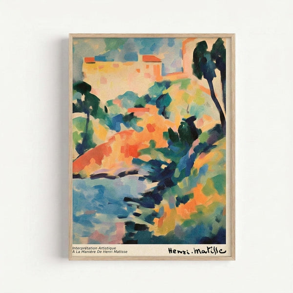 Colorful abstract landscape painting in light wood frame hanging on white wall. Features vibrant brushstrokes in blues, oranges, greens, and yellows depicting Mediterranean hillside with cypress trees and buildings. Fauve-style artwork with bold, expressive colors and loose painterly technique. Bottom shows French text and artist signature.