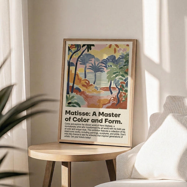 May include: Framed poster print featuring a colorful tropical landscape with palm trees in Matisse's distinctive style, displayed on a round wooden side table next to a beige upholstered chair. Natural sunlight streams across white walls, creating soft shadows. A plant's leaves are visible in the corner, adding to the serene interior setting.