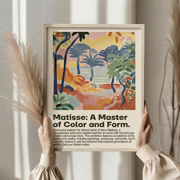 May include: Person holding framed poster featuring vibrant tropical landscape with palm trees, colorful foliage in blues, greens, yellows and coral tones, painted in bold Fauvist style. Light wood frame against white curtained background with dried pampas grass stems visible. Exhibition-style text below artwork describes Matisse master of color and form show.