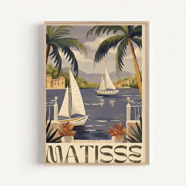 Framed vintage-style poster featuring a Mediterranean coastal scene with sailboats on blue water, viewed through palm fronds and a white stone balcony with decorative posts. Warm buildings nestle among green hills in the background under a cloudy sky. Orange flowers in white planters accent the foreground. The word "MATISSE" appears in large brown letters at the bottom. Light wood frame against white wall.