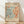 May include: Framed vintage-style exhibition poster featuring abstract organic shapes in coral orange and teal blue on cream background. The artwork shows flowing, leaf-like cutout patterns reminiscent of Matisse's paper collage style. Wooden frame leans against white wall on light wood flooring with soft natural lighting creating gentle shadows.