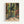May include: Framed art print showing tropical interior scene with large windows overlooking lush green jungle foliage, colorful palm fronds and exotic plants visible through glass panes, decorative patterned floor tiles in coral and teal, vibrant botanical wallpaper or curtains with orange and red tropical flowers, artist name "Henri Matisse" printed at bottom, displayed in light wood frame against white wall