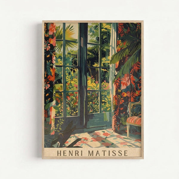 May include: Framed art print showing tropical interior scene with large windows overlooking lush green jungle foliage, colorful palm fronds and exotic plants visible through glass panes, decorative patterned floor tiles in coral and teal, vibrant botanical wallpaper or curtains with orange and red tropical flowers, artist name "Henri Matisse" printed at bottom, displayed in light wood frame against white wall