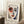 May include: Framed art print featuring an abstract portrait with bold brushstrokes in red, blue, and white tones, showing a stylized face with prominent eyes and red lips. The poster has "HENRI MATISSE" text at the top and includes a quote at the bottom. Displayed in a light wood frame leaning against white walls on a textured cream rug, with a coffee cup on books nearby and soft natural lighting creating shadows.