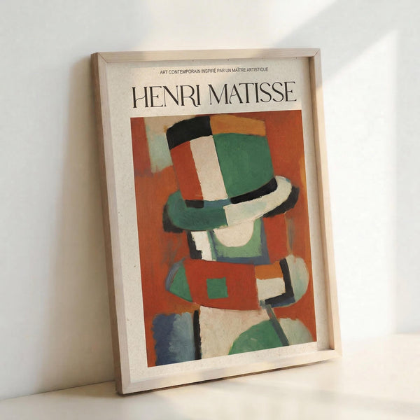 Framed vintage-style art poster featuring Henri Matisse's abstract modernist painting with geometric shapes in vibrant colors including green, orange, red, blue, and cream. The artwork shows angular, overlapping forms suggesting a stylized figure or portrait. Displayed in a light wooden frame leaning against a white wall, creating soft shadows. The poster has French text at the top and showcases Matisse's characteristic bold color palette and simplified forms.