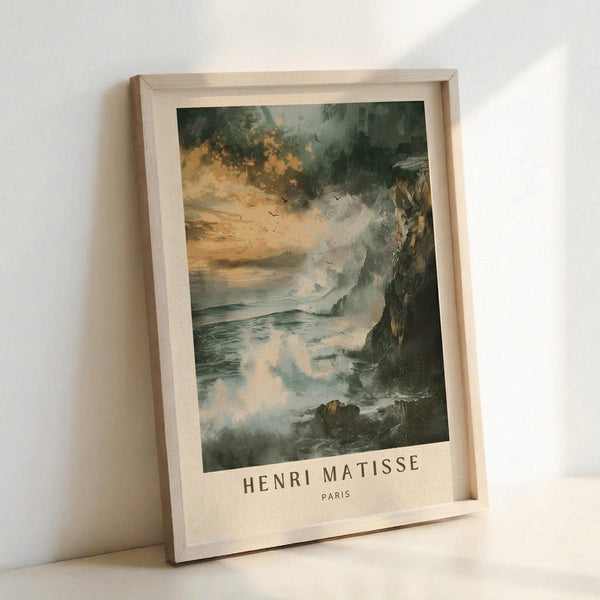 May include: Framed poster print leaning against white wall showing dramatic coastal seascape with stormy skies in golden yellow and dark green tones, rocky cliffs on right side, turbulent ocean waves, and flying birds. Text reads "HENRI MATISSE PARIS" below artwork. Natural wood frame with light finish sits on white surface with soft shadows.