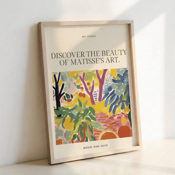 May include: Framed art poster with cream background displaying colorful abstract forest scene in Matisse's style, featuring vibrant green foliage, purple and black tree trunks, yellow and orange circular shapes, and blue botanical elements. Text reads "Discover the Beauty of Matisse's Art" above the artwork. Natural wood frame leans against white wall on light surface, casting soft shadows.