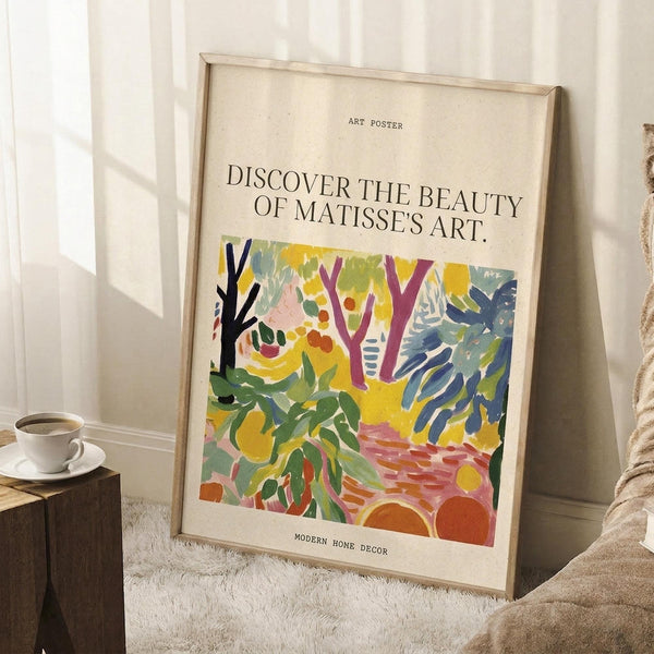 May include: Framed art poster leaning against white wall on textured white rug. Features colorful abstract landscape with green foliage, purple tree branches, yellow and blue brushstrokes, and orange circular elements in Matisse's distinctive style. Text reads "Discover the Beauty of Matisse's Art" above artwork and "Modern Home Decor" below. Natural wood frame, cozy room setting with coffee cup on wooden block and beige blanket visible.